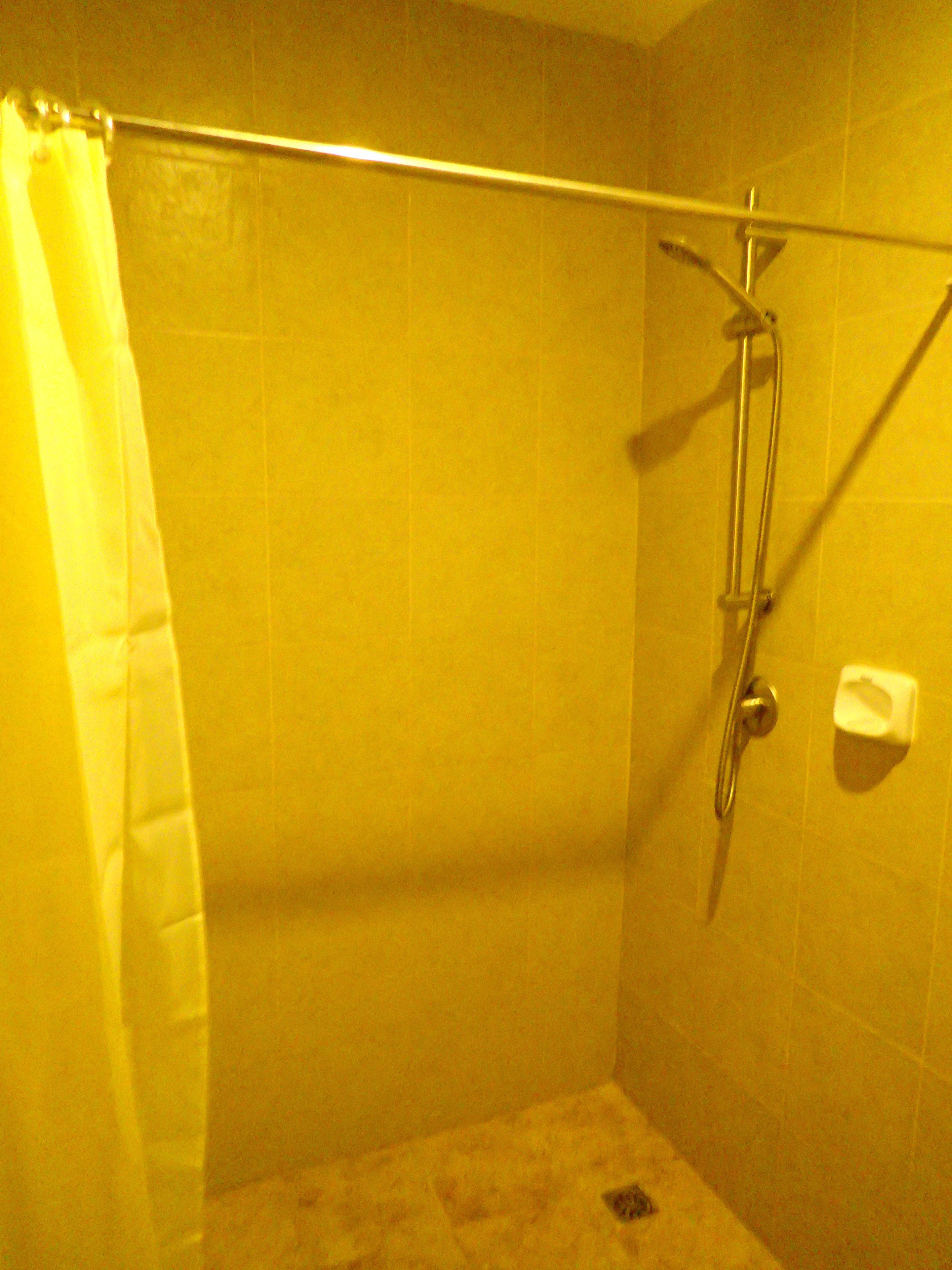 Un petit espace douche fermé, équipé d’un pommeau de douche et d’un distributeur de serviettes.