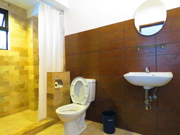 A bathroom with a toilet, a sink, and a shower area. - Aozora Seaside Mactan (Lapu-Lapu)