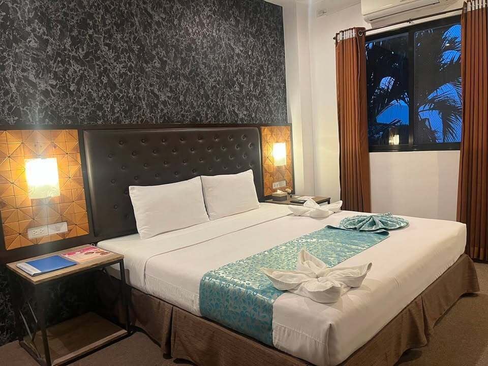 Ein Hotelzimmer mit einem großen Bett, zwei Nachttischen, einem Fenster mit Vorhängen.