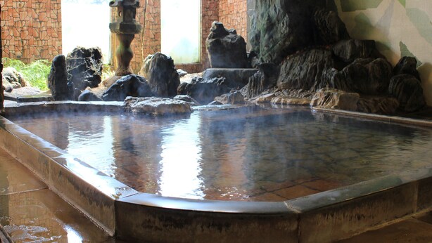 A hot spring area with a stone fountain, rocky formations, and a tiled floor. - Marumo (Tottori)