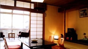 A traditional Japanese room with tatami flooring, a low table, and a sliding door. - Marumo (Tottori)