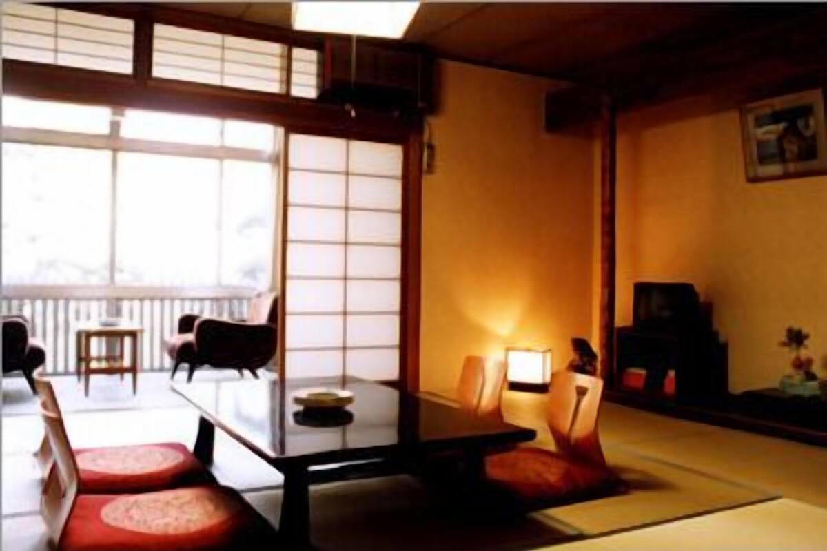 Um quarto japonês tradicional com tatames, uma mesa baixa e um portas correderas.