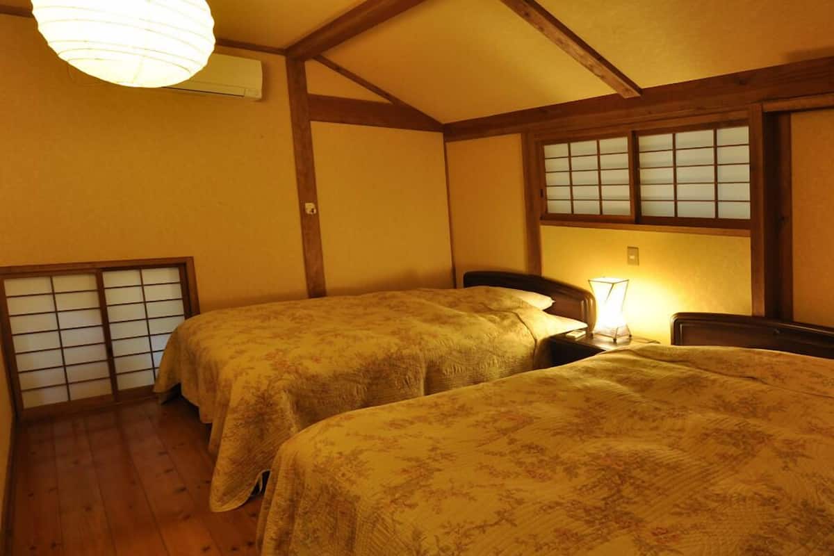 Une pièce de style japonais traditionnel, dotée de deux lits, d’un plancher en bois, d’un paravent shoji et d’une porte coulissante.