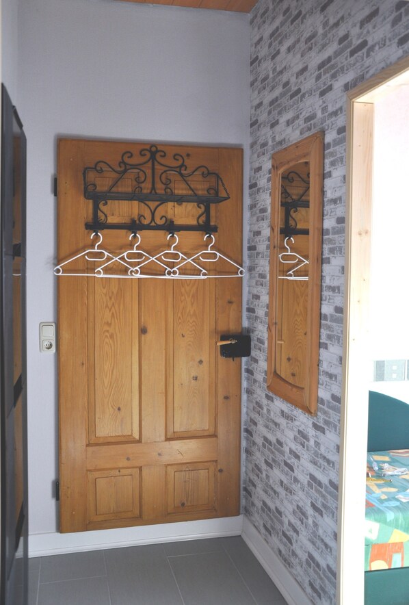 A wooden door with a metal hanger rack above it, set against a brick-patterned wall.
