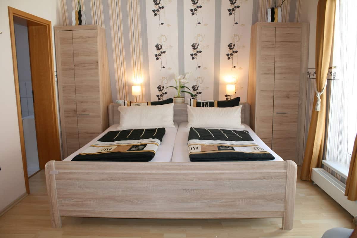Ein Doppelbett mit Holzbettgestell, zwei Nachttische und eine Wand mit floralem Tapetenmuster.