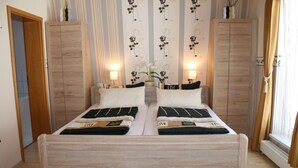 Una cama doble con estructura de madera, dos mesitas de noche y una pared con papel tapiz floral.