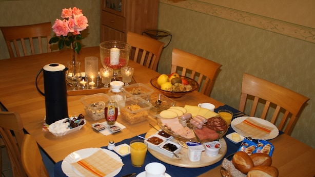 Un desayuno con diversos alimentos, como pan, frutas y una mesa iluminada con velas.