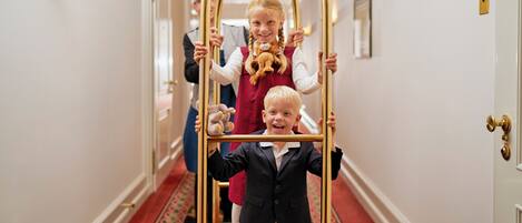 A hallway with a red carpet, white walls, and gold-framed decorative elements.