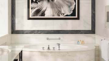 A modern bathroom with a large bathtub, a framed floral artwork on the wall, and a checkered floor pattern.