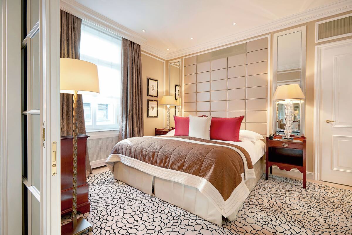 A hotel room with a large bed, a dresser, a nightstand, and a mirror.