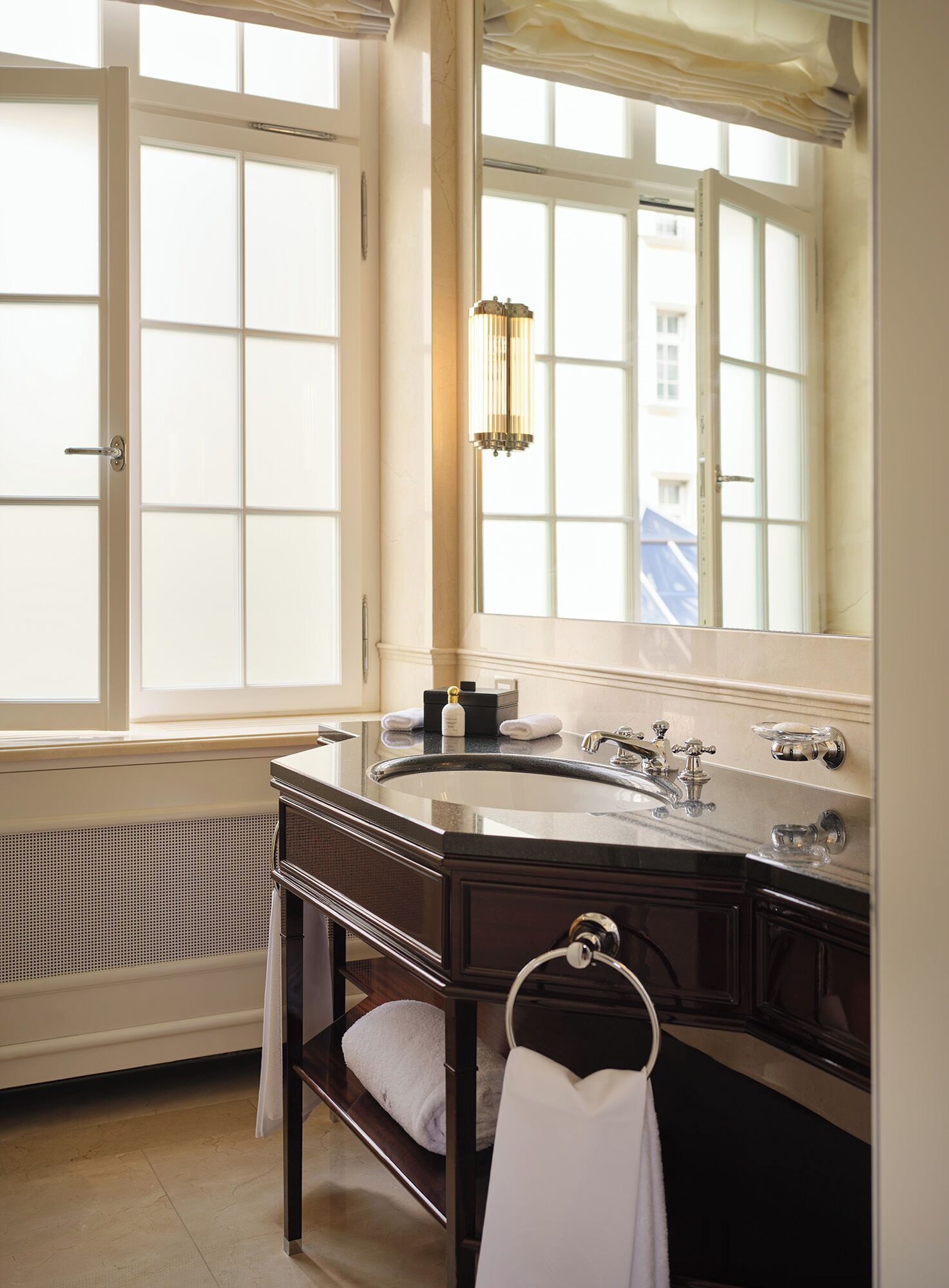 A bathroom with a large window, a sink, a mirror, and a towel rack.