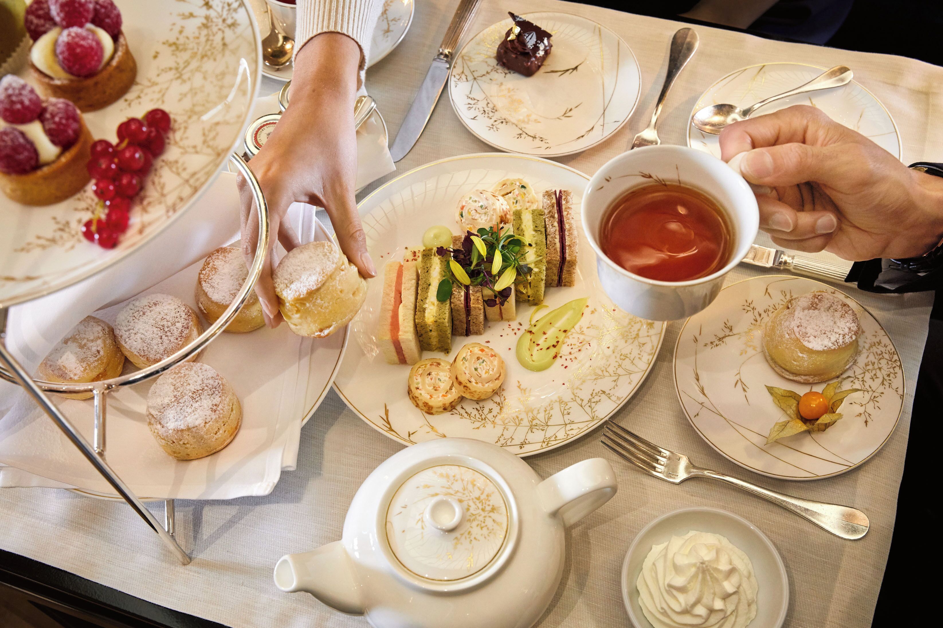 Une table dressée avec diverses pâtisseries, une théière et une tasse de thé.
