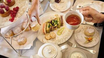Une table dressée avec diverses pâtisseries, une théière et une tasse de thé.