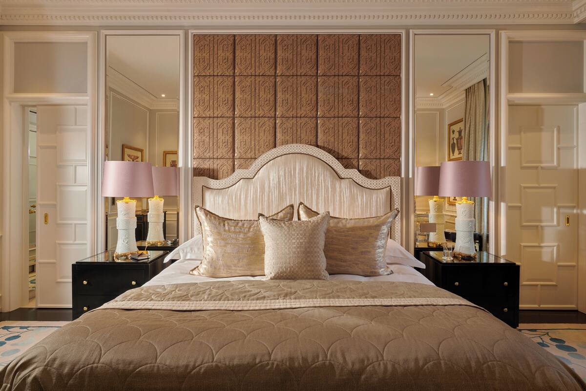A large bed with a quilted headboard, two bedside tables with lamps, and a mirror above the bed.