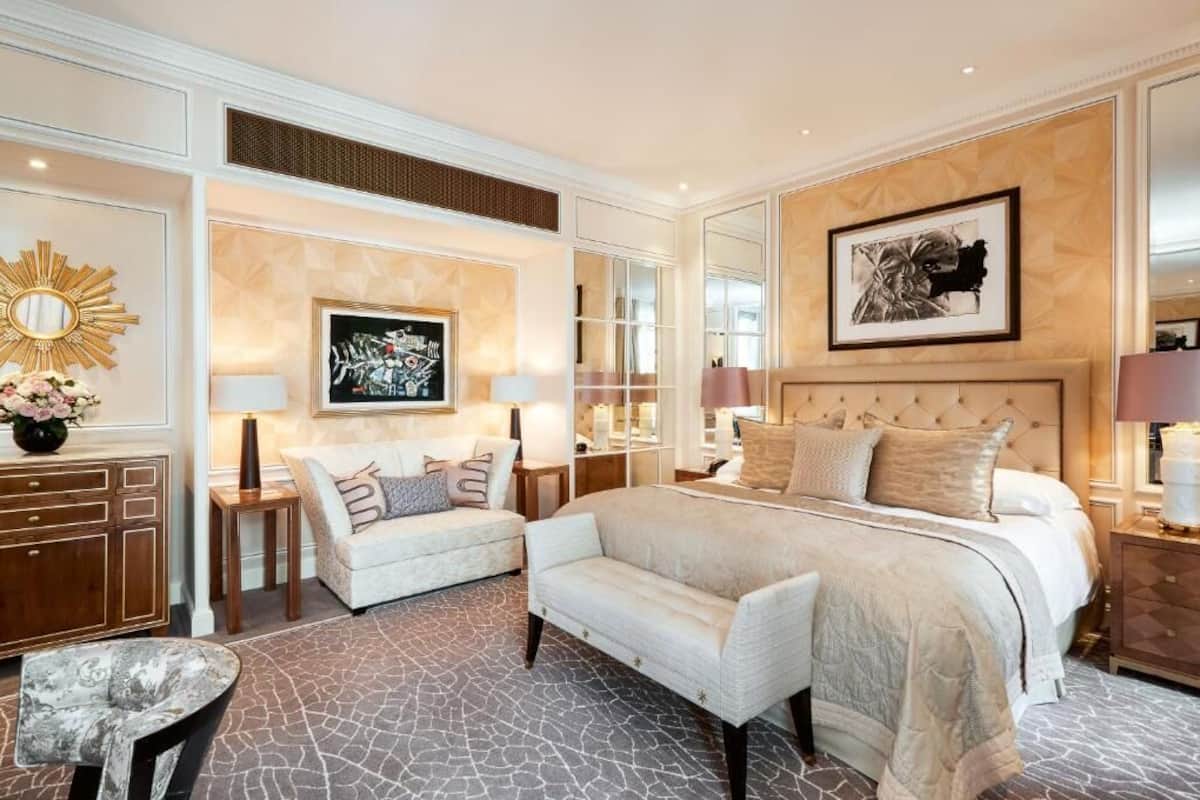 Ein geräumiges Schlafzimmer mit einem großen Bett, einer Couch, einem kleinen Tisch und einem dekorativen Spiegel.
