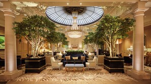 A grand lobby with a high ceiling, large chandelier, and symmetrical columns. - Baur au Lac (Zürich)