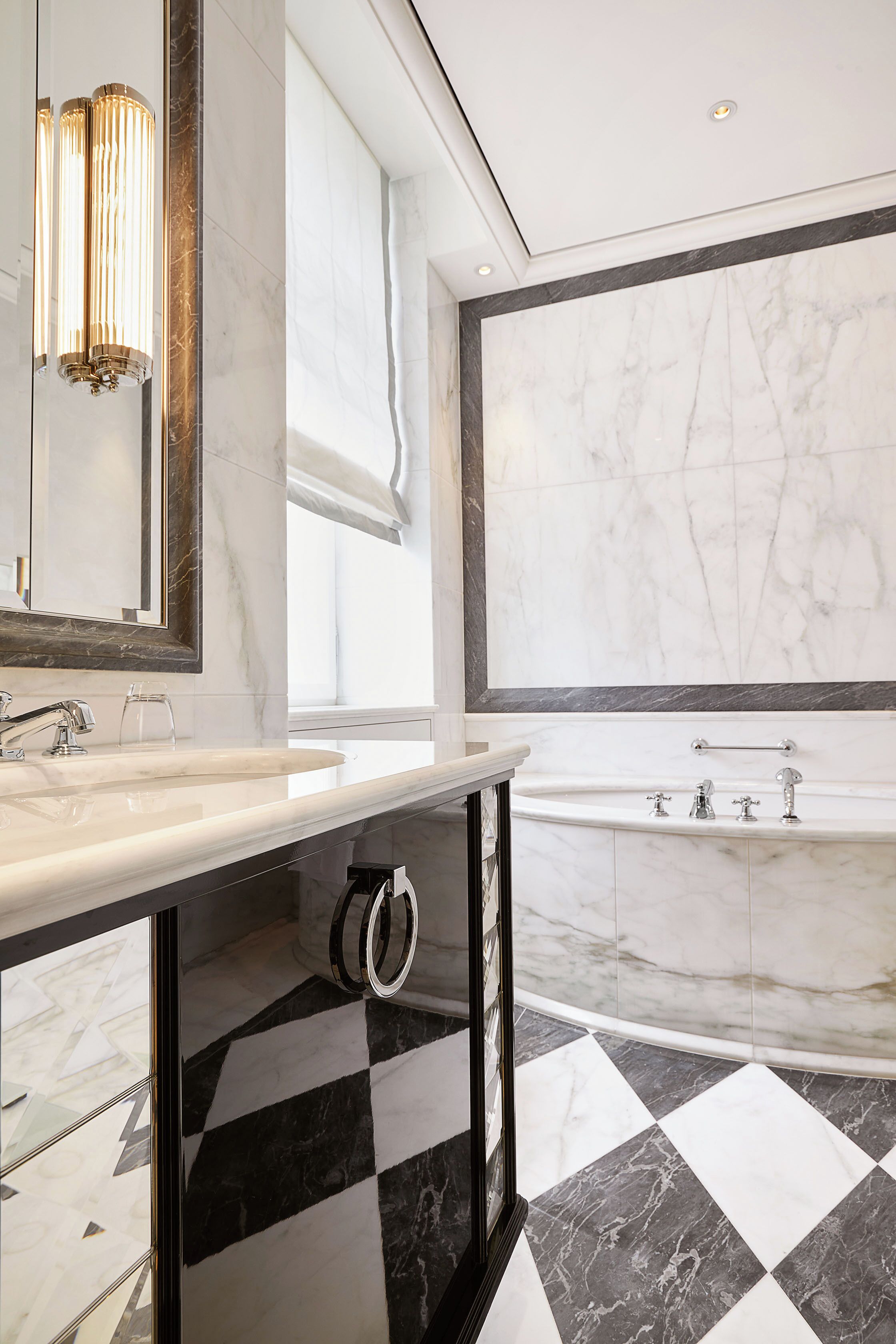 A modern bathroom with a large mirror, two sinks, a bathtub, and a checkered floor pattern.