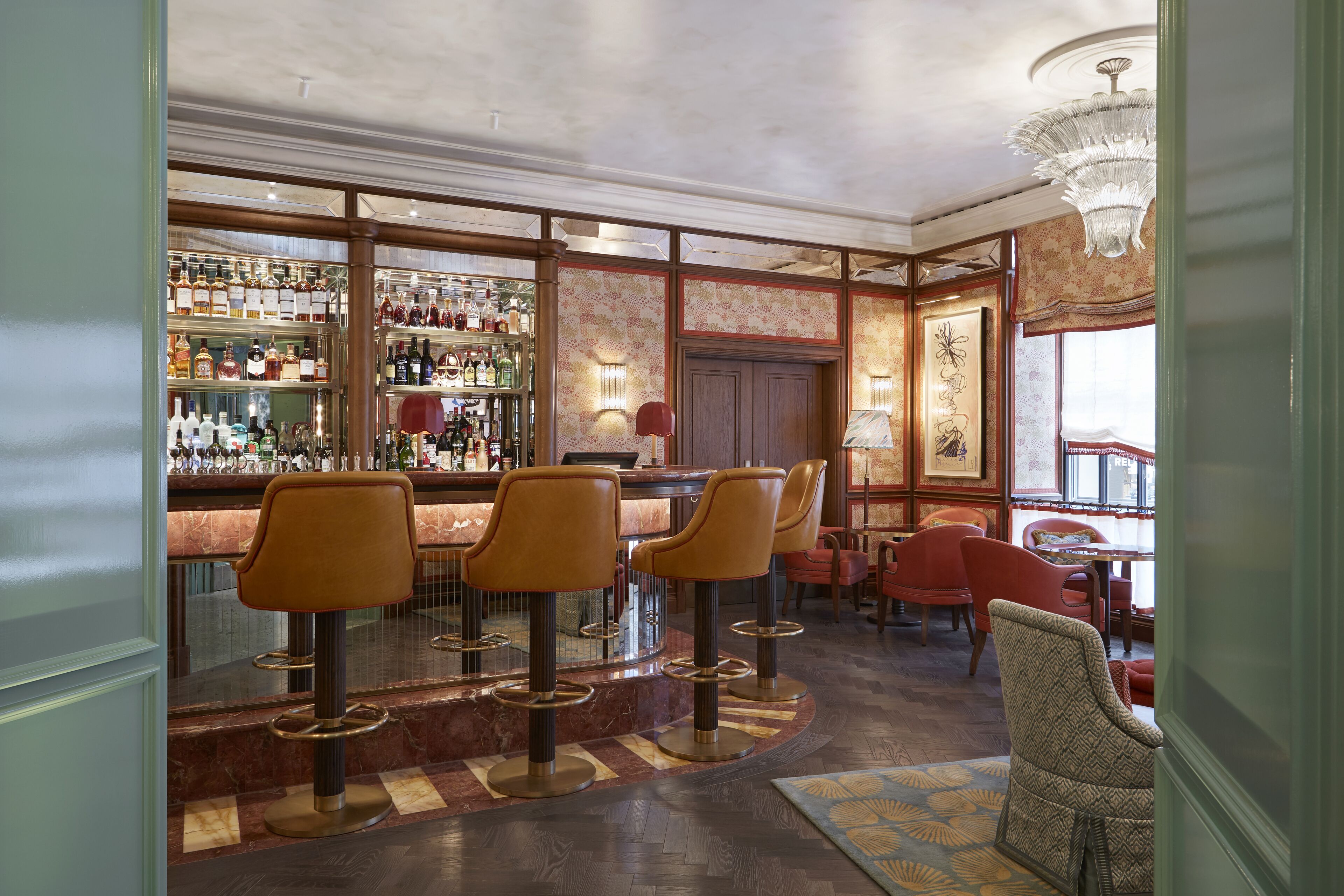 A bar area with multiple stools, a bar counter, and a variety of bottles.