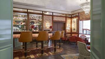 A bar area with multiple stools, a bar counter, and a variety of bottles.