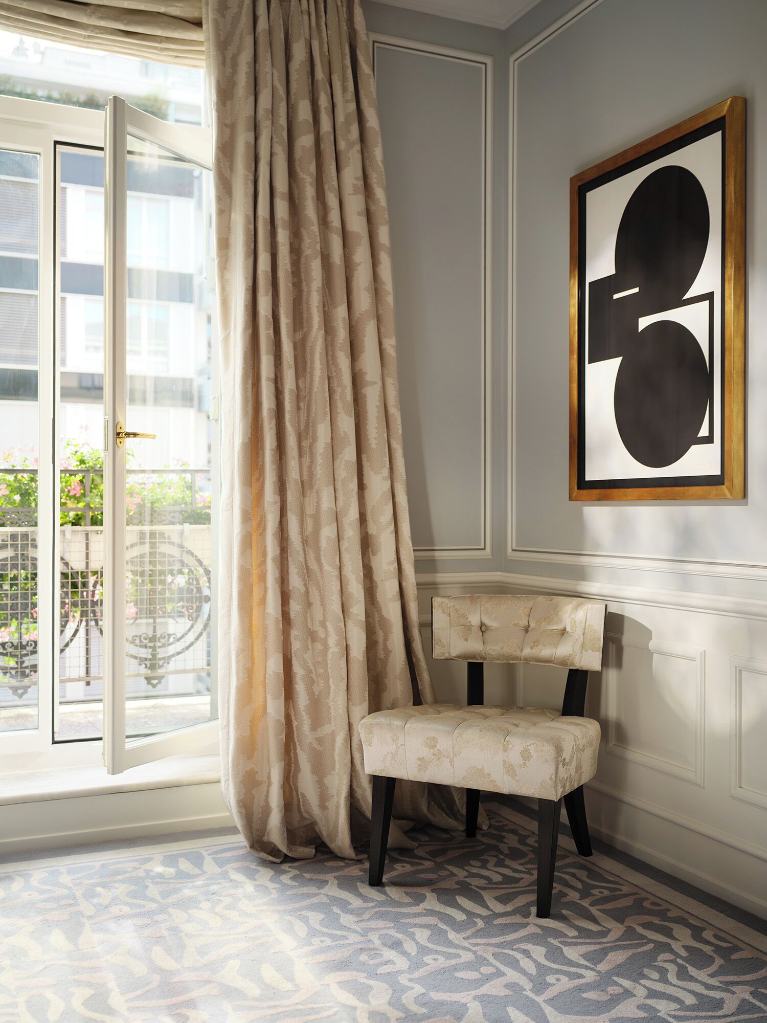 Una habitación con un ventanal amplio, una silla y una obra de arte enmarcada en la pared.