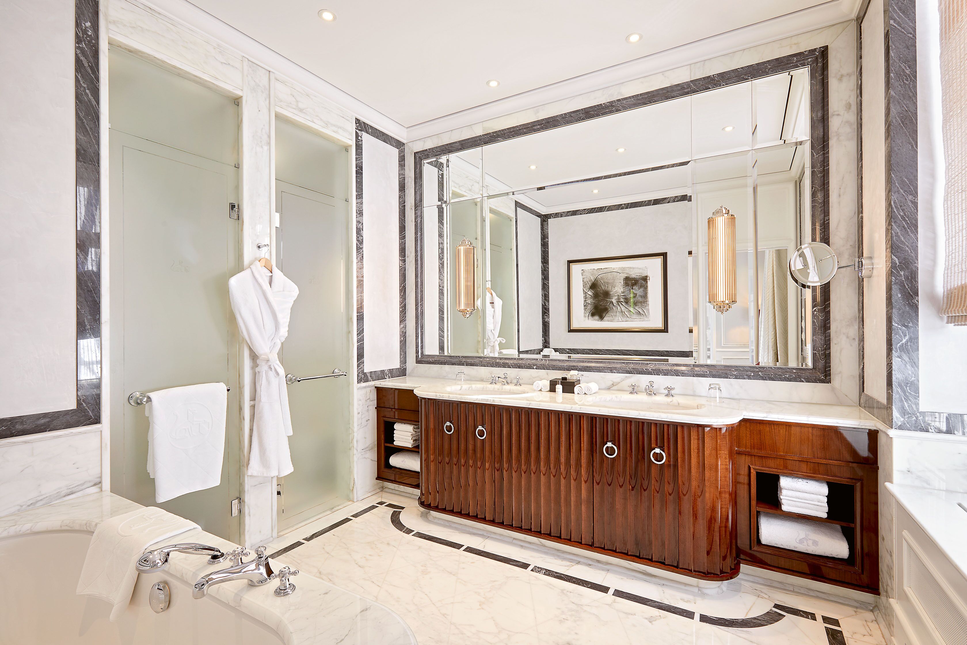 A modern bathroom with a large mirror, a bathtub, and a vanity with a wooden cabinet.