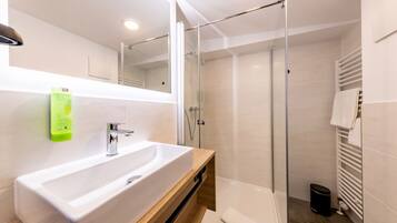 A modern bathroom with a large sink, glass shower enclosure, and a towel rack.