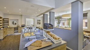 A modern breakfast area with a buffet setup, including bread, pastries, and beverages. - Hotel zur Börse (Hamelin)