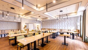 A conference room with long tables, chairs, and modern lighting fixtures. - Hotel zur Börse (Hamelin)