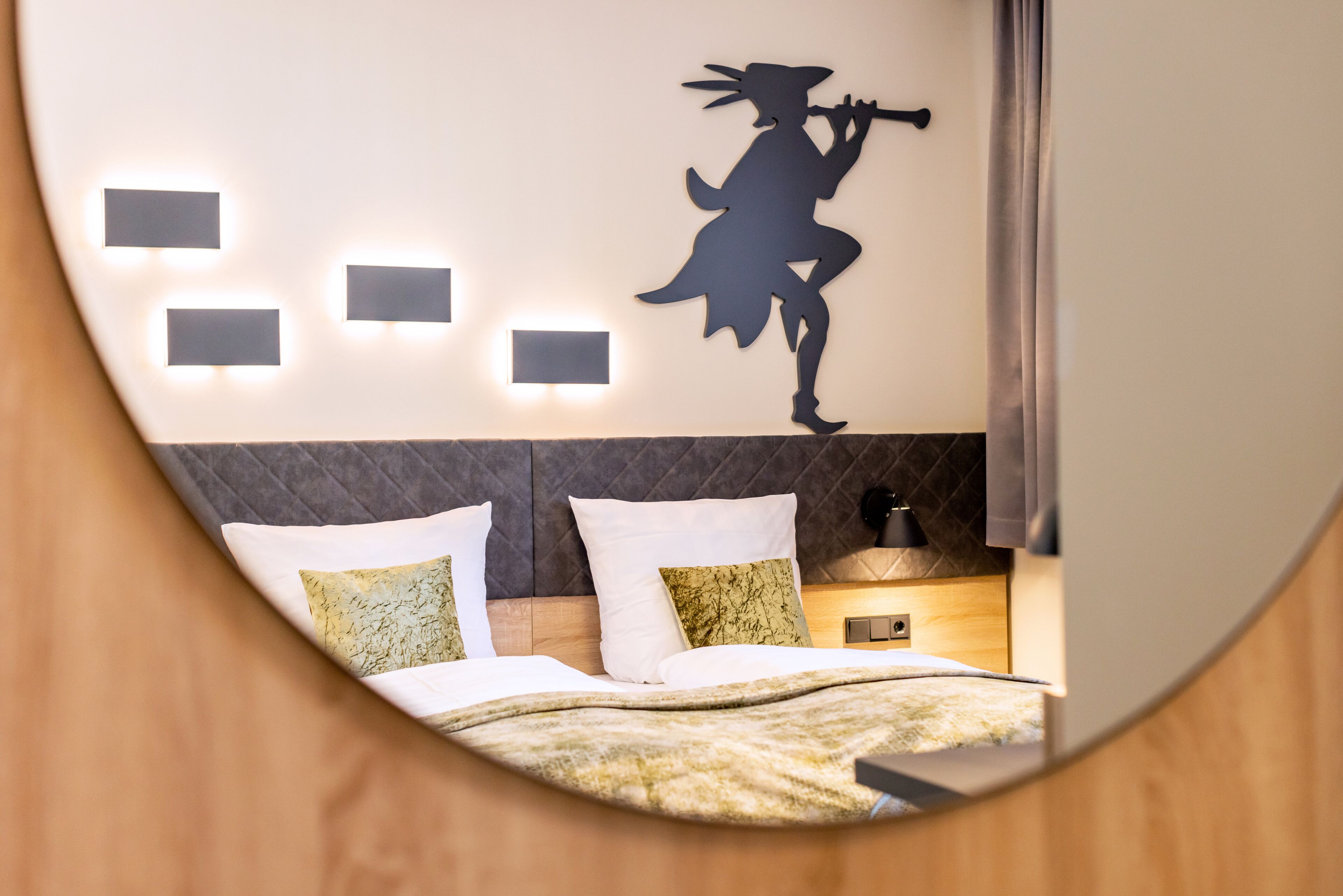 A modern hotel room with a bed, a nightstand, and a wall-mounted light fixture.