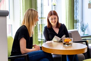 Two people sitting at a round table with a book and a glass of water. - Hotel zur Börse (Hamelin)