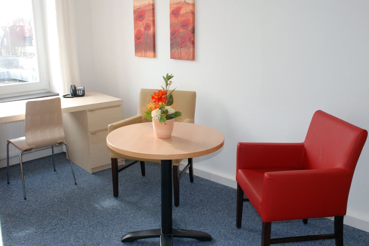 A modern office space with a round table, two chairs, a desk, and a telephone.
