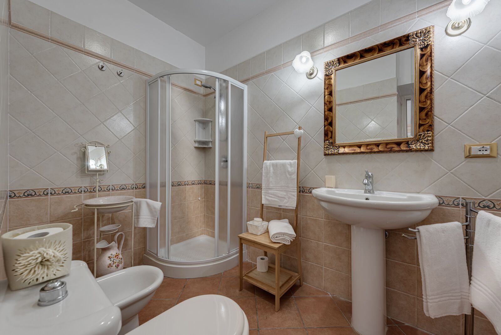 Un baño con ducha envuelta en cristal, lavamanos, inodoro y tocador con espejo.