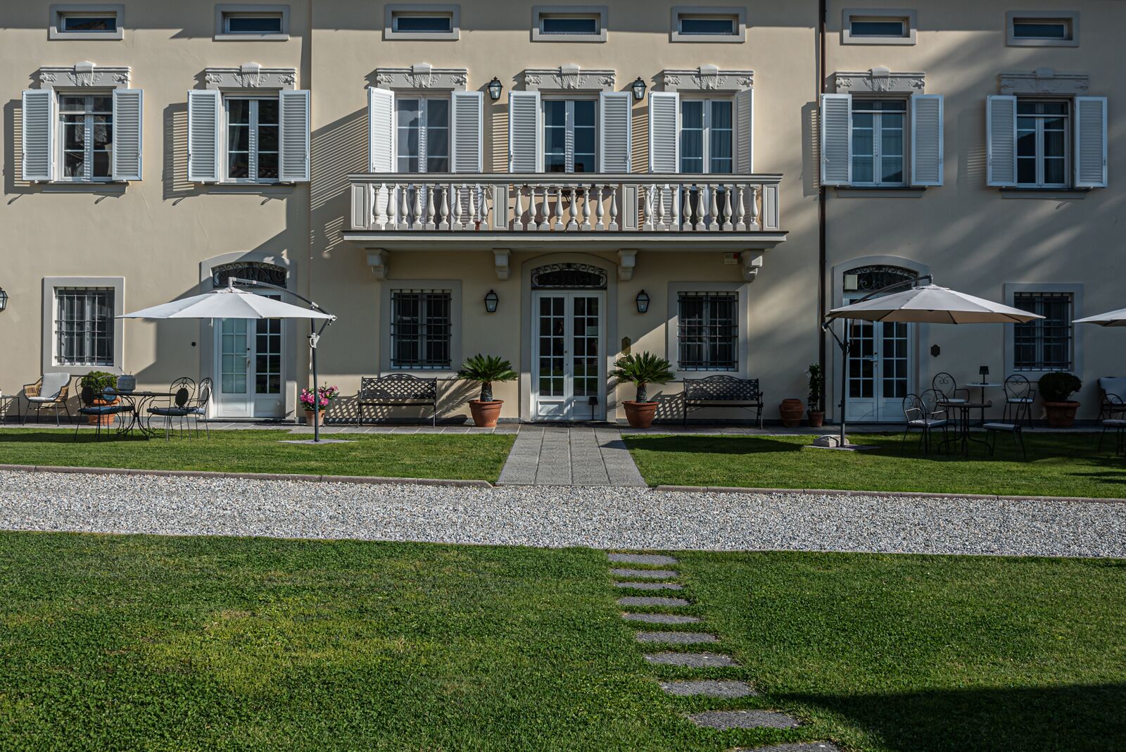 Un edificio con un ingresso centrale, piante in vaso, posti a sedere all'aperto e un vialetto ghiaioso.