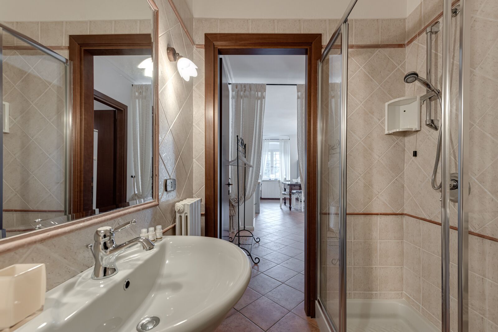 A modern bathroom with a large mirror, a sink, and a shower area.