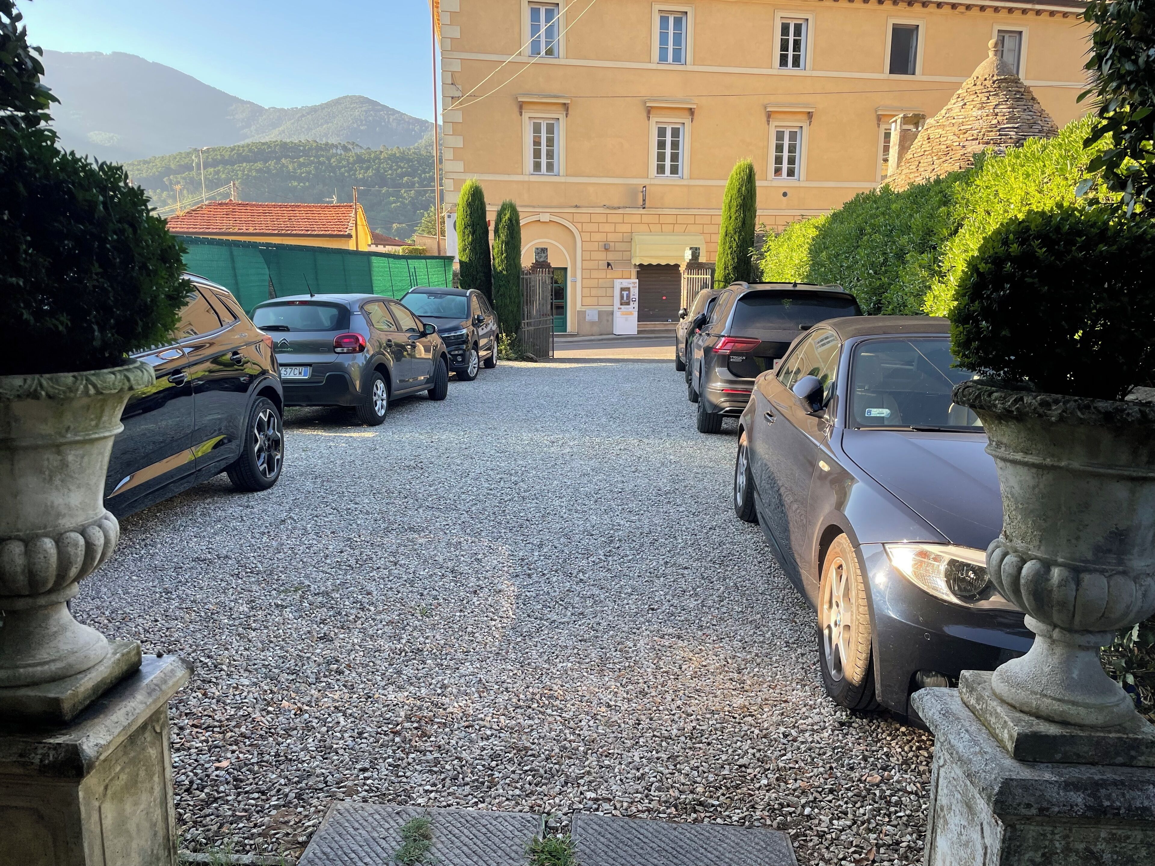 A gravel driveway leading to a building with parked cars.
