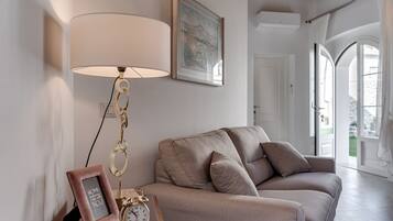 A living room with a sofa, a lamp, a clock, and a framed picture on a side table.