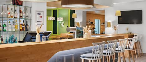 Eine Bar mit Holztresen, Barhocker und einer Auswahl an Spirituosenflaschen.
