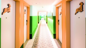 A hotel corridor with green and white walls, numbered doors, and a patterned floor. - Hey Lou Hotel Piding (Piding)