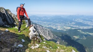 A person sitting on a rocky mountain edge with a view of a valley below. - Hey Lou Hotel Piding (Piding)