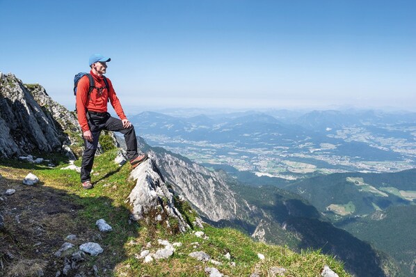 A person sitting on a rocky mountain edge with a view of a valley below. - Hey Lou Hotel Piding (Piding)