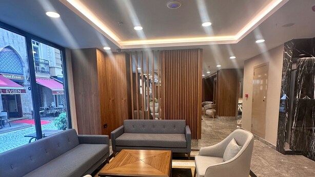 A modern hotel lobby with a sofa, chairs, a coffee table, and a view of the street outside. - Hotel Sapphire (Istanbul)