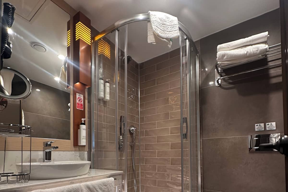 Un baño moderno con cabina de ducha de vidrio, un lavamanos con espejo y un inodoro.