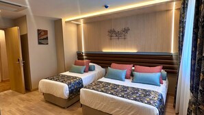 A modern bedroom with two beds, wooden flooring, and a ceiling with recessed lighting. - Hotel Sapphire (Istanbul)