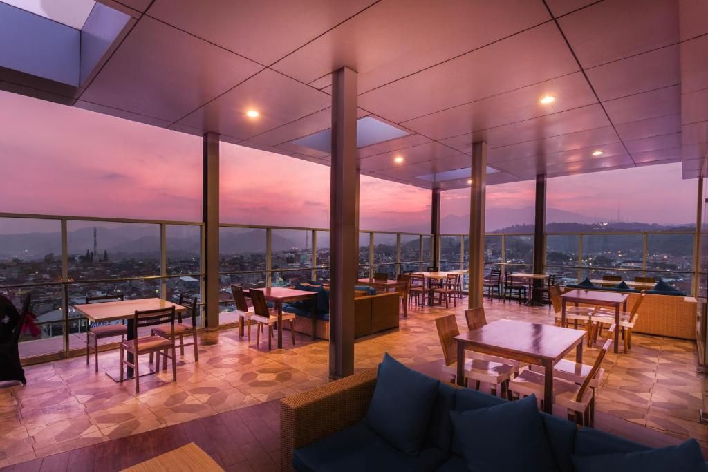 A rooftop dining area with tables and chairs, large windows, and a view of the cityscape.