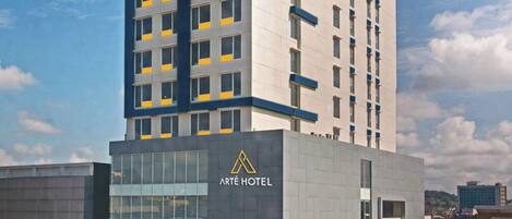 Un moderno edificio de hotel con un llamativo letrero de Arté Hotel, varios pisos y fachada de vidrio.