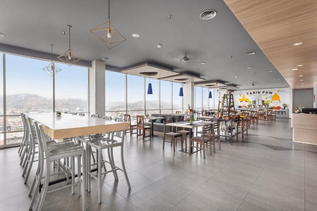 A modern dining area with a large table and chairs, a kitchen area, and a mural on the wall.