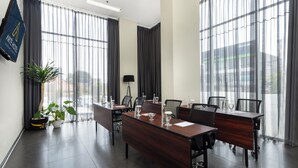A conference room with a long table, chairs, and a potted plant.