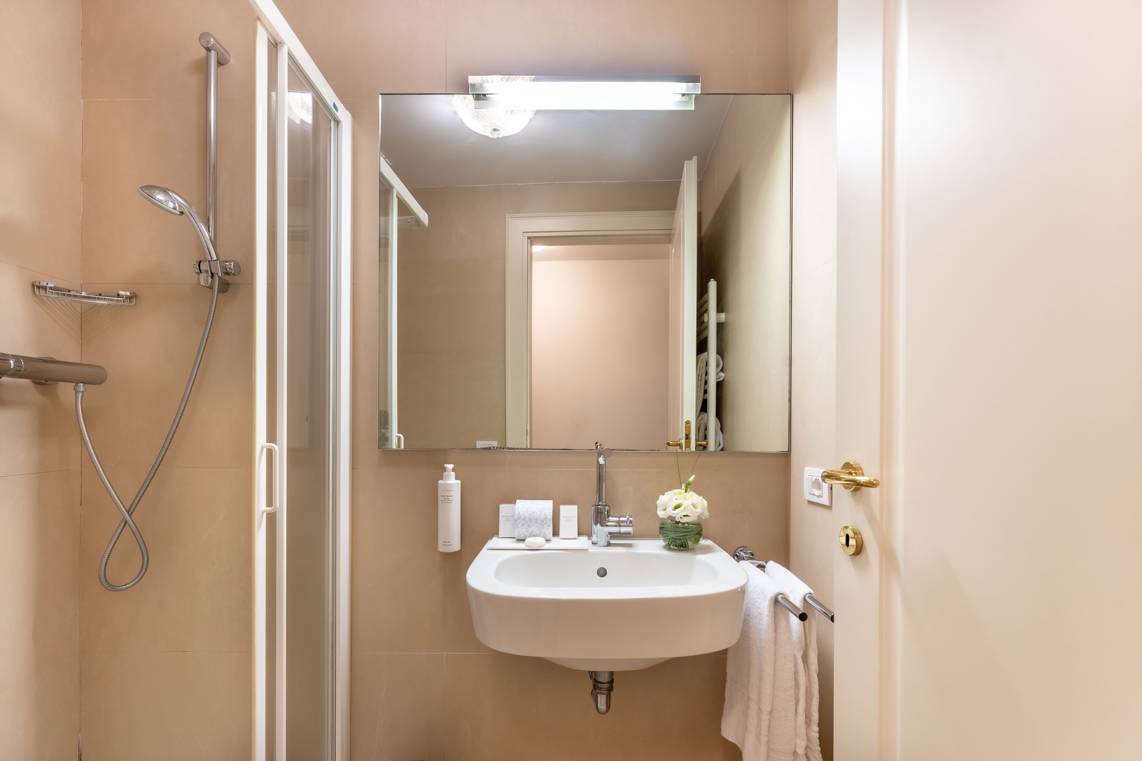 A bathroom with a sink, mirror, shower, and towel rack.