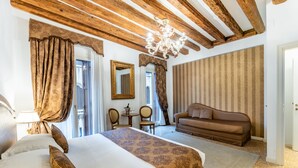 Habitación de hotel con una cama grande, un sofá, una araña de cristal y vistas al exterior.
