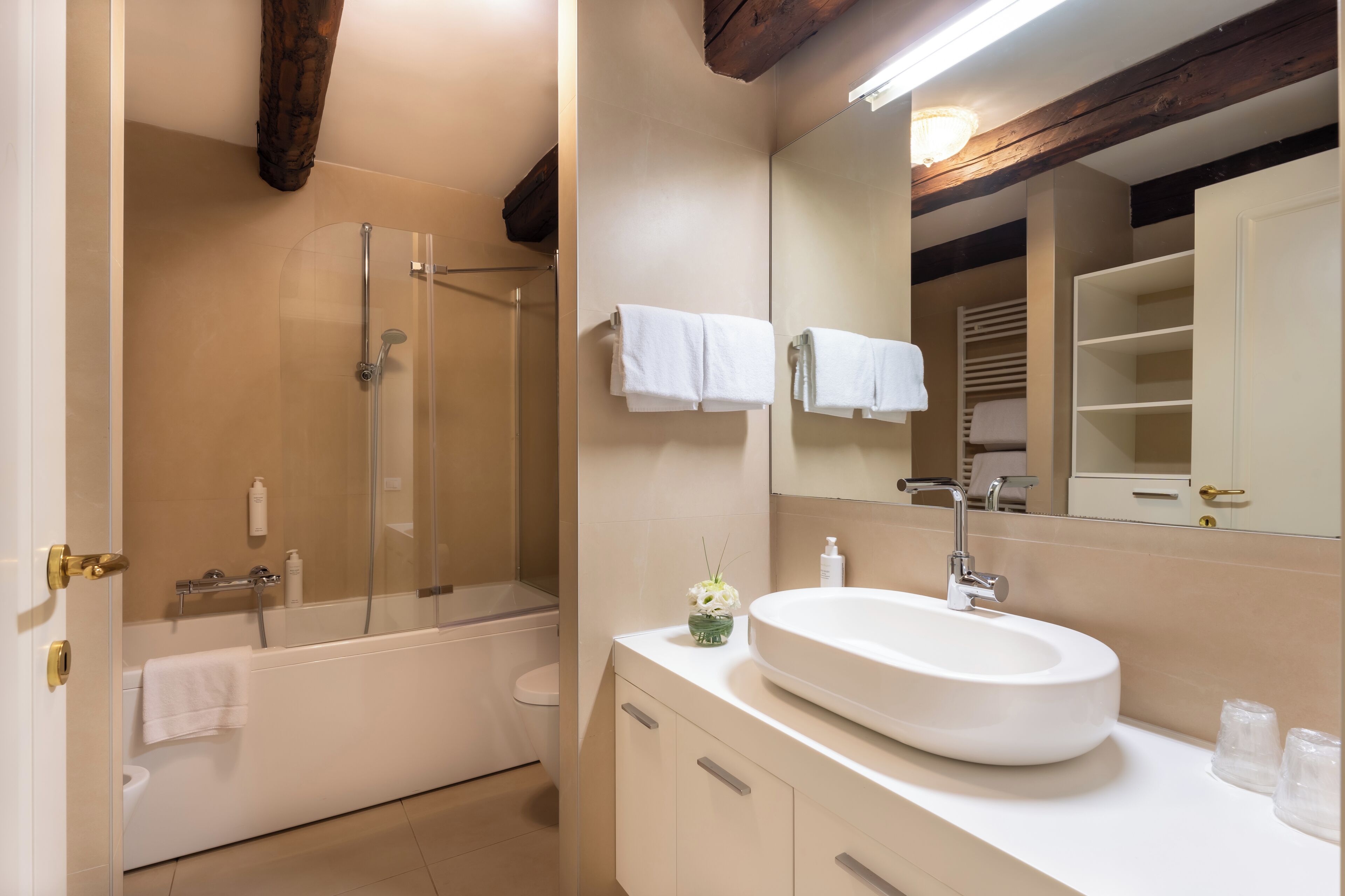 A modern bathroom with a glass-enclosed shower, a white sink, and a large mirror.